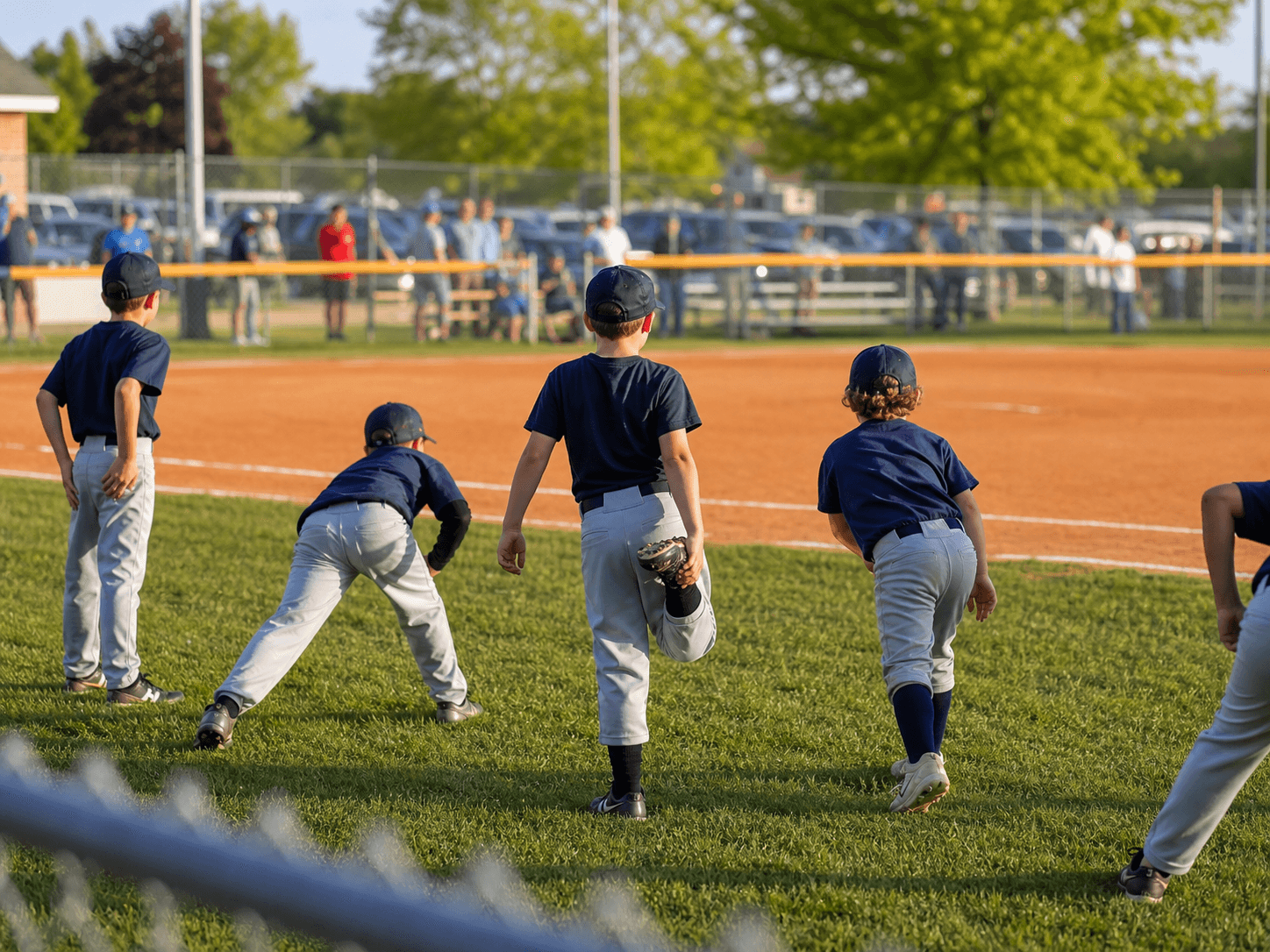 Youth baseball players warming up on the grass before a game.